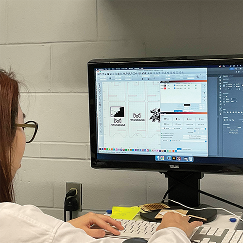 Laser cutting technician putting my files into the computer to start cutting it.